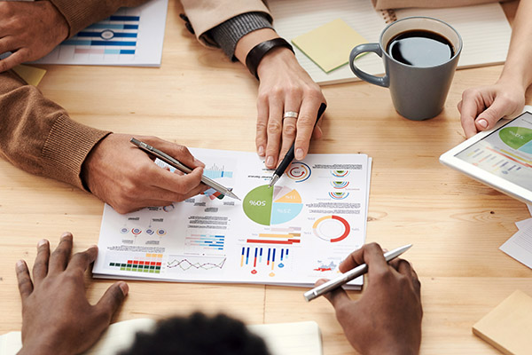 View of people's hands pointing at charts and holding documents.